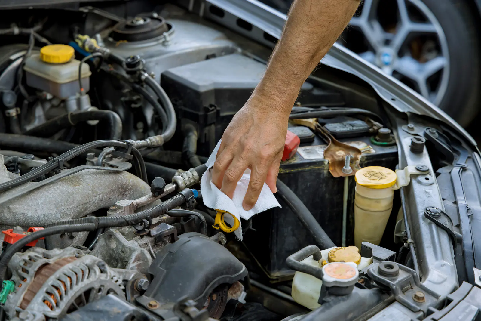 Person cleaning the inside of the engine bay of a vehicle